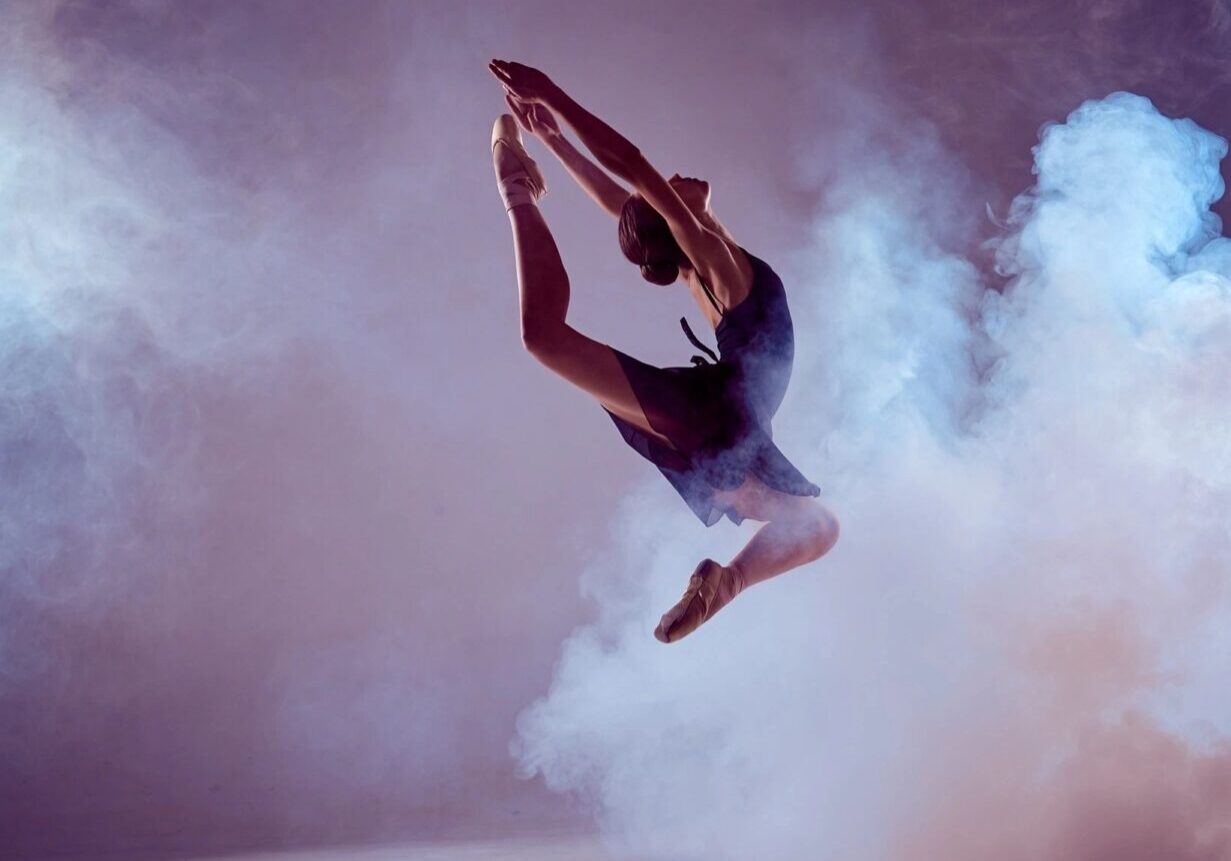 A person jumping in the air with smoke coming from behind them.